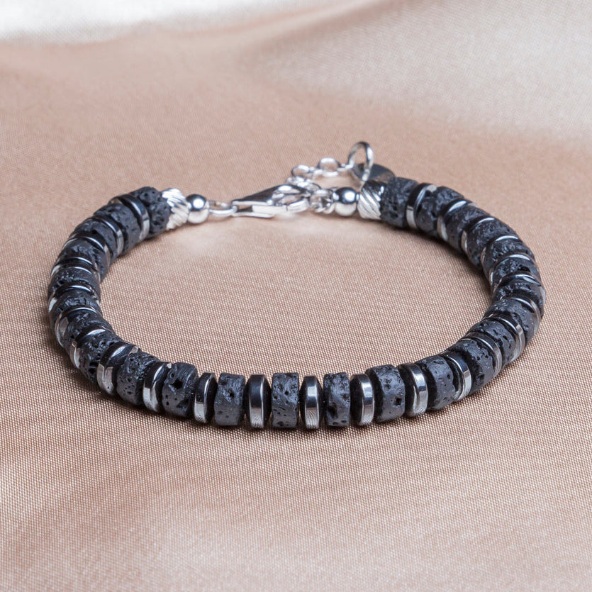 Bracciale Magma artigianale in pietra lavica, ematite e argento 925 rodiato su sfondo tessuto, Lab93Studio
