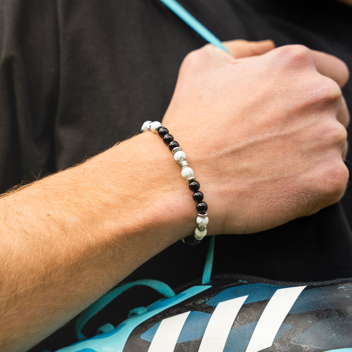 Bracciale artigianale da uomo indossato. Realizzato con aulite bianca e onice nero. Lab93Studio