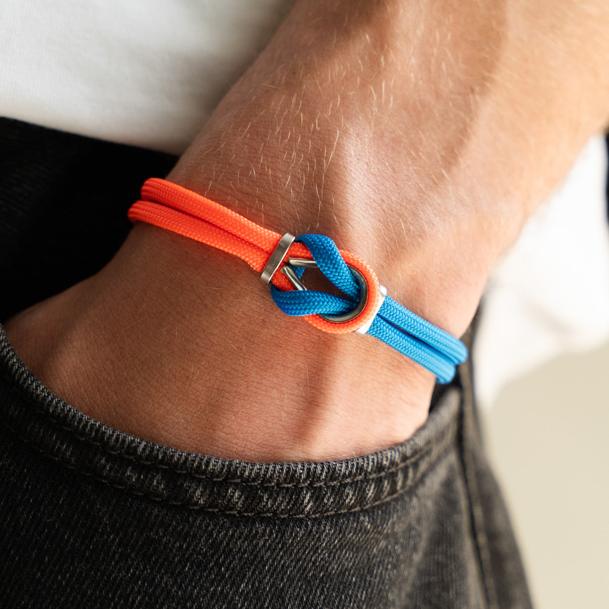 Bracciale Portofino Leone in paracord rosso e blu indossato al polso sinistro con jeans, Lab93Studio