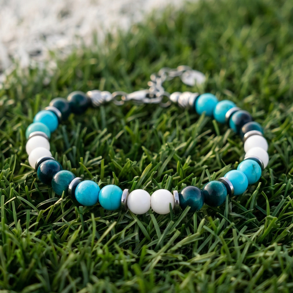 Bracciale artigianale da uomo su prato. Realizzato con occhio di tigre blu, agata bianca e aulite azzurra. Lab93Studio