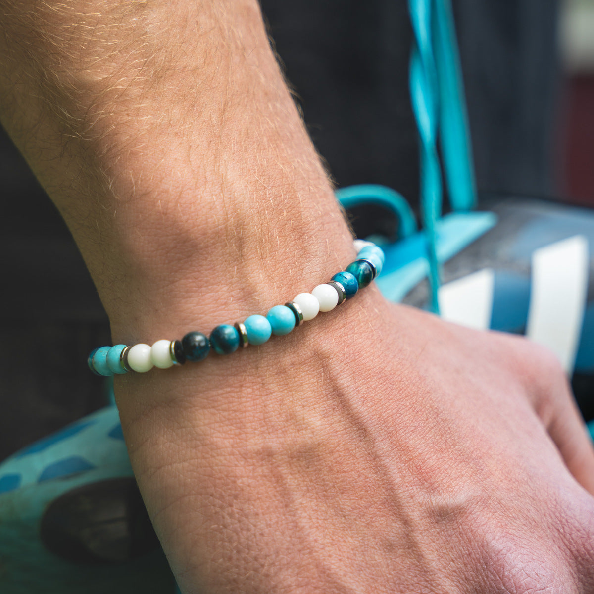 Bracciale artigianale da uomo indossato. Realizzato con occhio di tigre blu, agata bianca e aulite azzurra. Lab93Studio