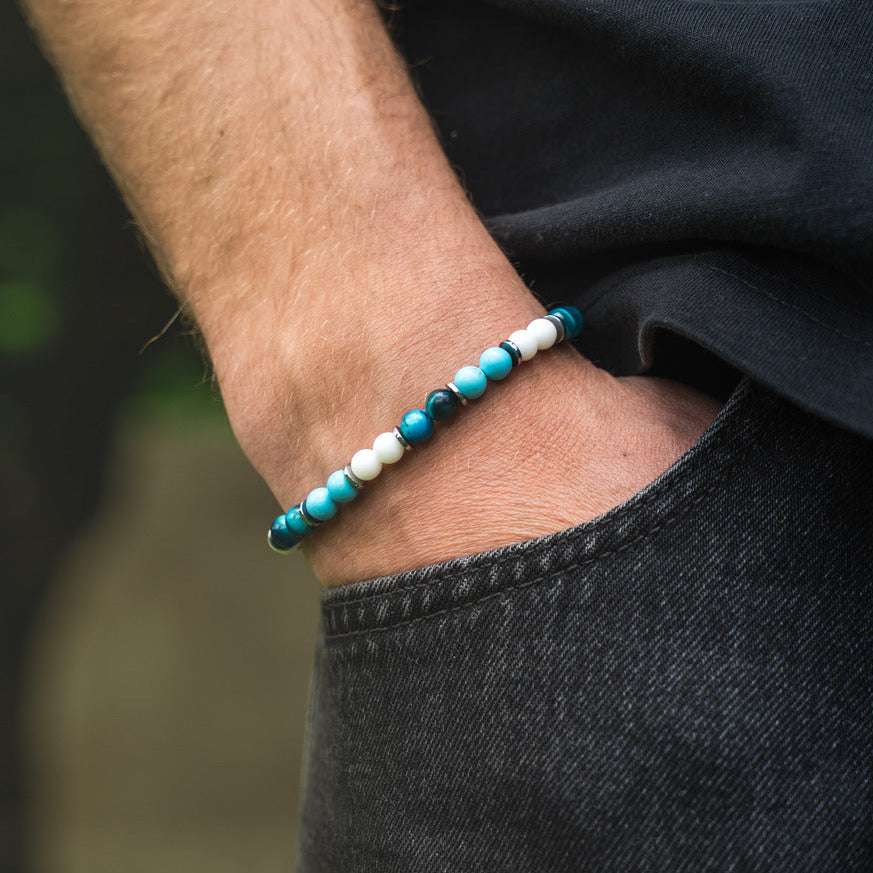 Bracciale artigianale da uomo indossato. Realizzato con occhio di tigre blu, agata bianca e aulite azzurra. Lab93Studio