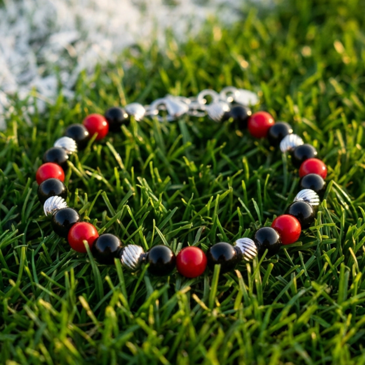 Bracciale artigianale da uomo su prato. Realizzato con onice nero e corniola rossa. Lab93Studio