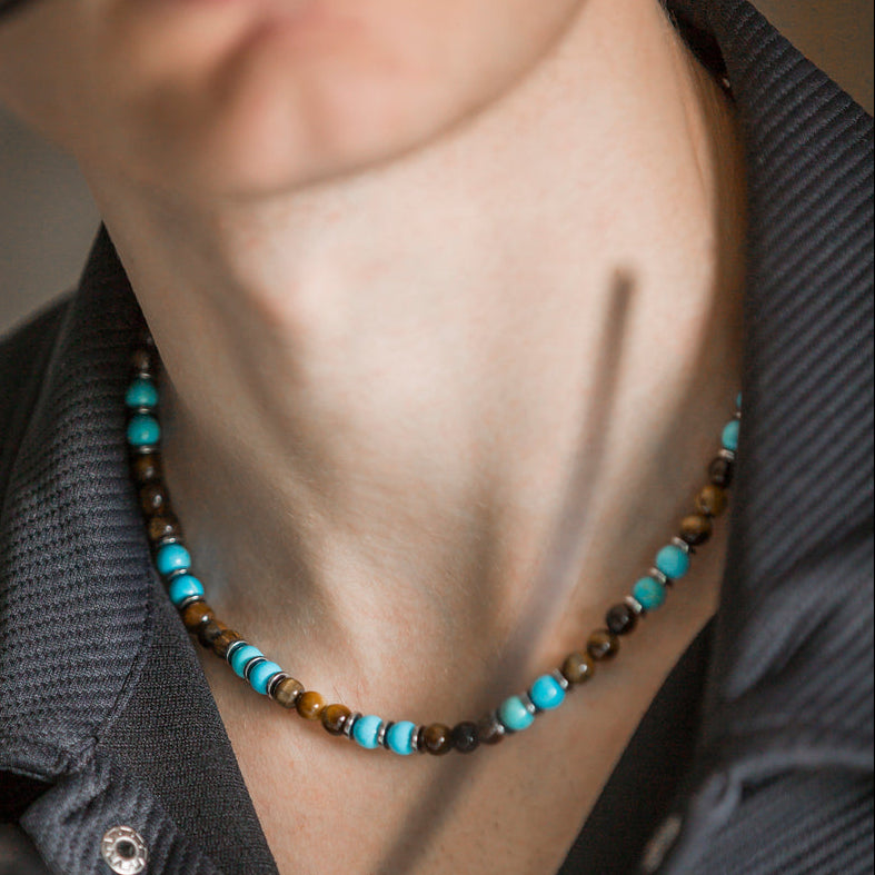 Collana Respiro Mediterraneo artigianale in aulite turchese e occhio di tigre indossata sul collo, Lab93Studio